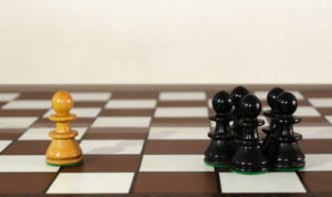 Wooden chess pieces grouped and single one. Bullyng and discrimination concept.
